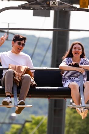 A Smiling Man and Woman posing for the camera on the scenic chairlift at The Highlands