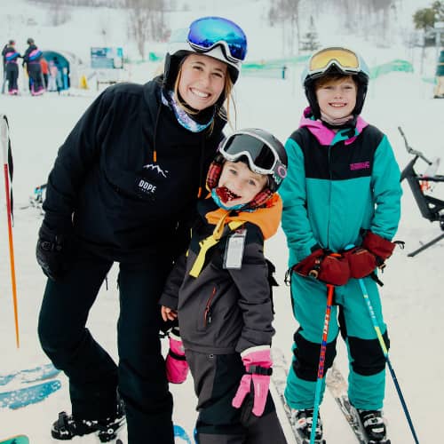 A mom and two children in ski gear posing at The Highlands