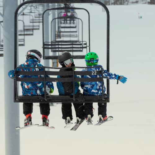 Three children skiers on a chairlift at The Highlands